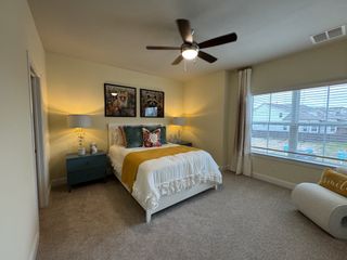 Model Home Elegant bedroom with large windows, neutral tones, a king-sized bed, cozy seating, and stylish decor.
