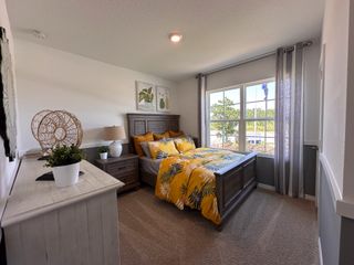A cozy bedroom with a rustic wooden bed frame, bright yellow bedding, and large windows that fill the space with natural light.