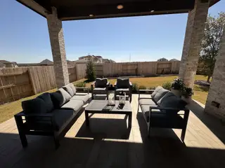 A cozy outdoor patio featuring plush seating and a serene fenced backyard, perfect for relaxation and entertaining.