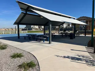 A modern community pavilion with picnic tables beside a sports court in Mandarin at Citrus Park by Landsea Homes (Goodyear, AZ).