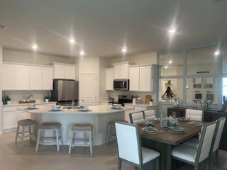 A modern kitchen and dining space with white cabinetry, an island, sleek appliances, and elegant seating for gatherings.