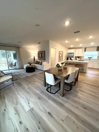 An open-concept living space with wood flooring, cozy seating, and a stylish dining area connected to a modern kitchen.