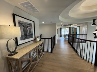 Model Home A contemporary hallway features sleek wood flooring, elegant lighting, and modern art, creating a warm and inviting ambiance.