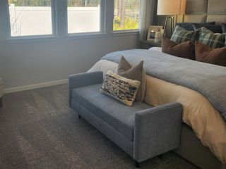 A cozy bedroom with large windows, a plush bed, and elegant decor, offering a tranquil retreat with natural light.