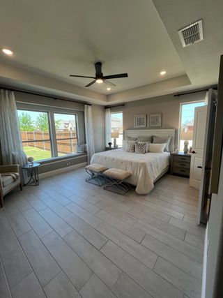 Model Home Spacious bedroom with a cozy bed, large windows, and sleek tile flooring, complemented by modern lighting and decor.