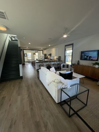 An open-concept living area with modern furnishings, wood flooring, and a stylish kitchen with island seating.