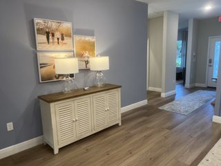 A welcoming hallway with light wood floors, a stylish sideboard, and family photos, creating a cozy atmosphere.