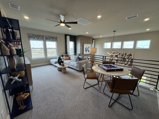 Model Home A modern loft area featuring a cozy sectional sofa, stylish decor, and a game table with chairs.