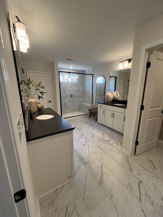 Model Home A modern bathroom with marble flooring, sleek black countertops, and elegant lighting.
