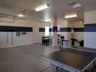 Model Home A spacious game room with a ping pong table, modern lighting, and bar area, ideal for entertaining and relaxing.