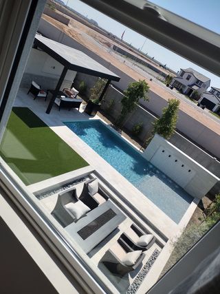 Model Home A luxurious backyard view featuring a sleek pool, elegant pergola, and stylish outdoor seating.