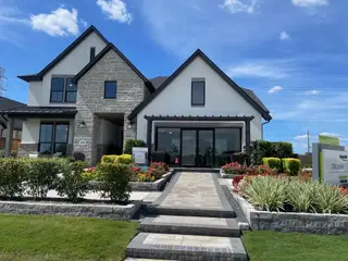 Model Home A modern stone and white facade home with lush landscaping in Trillium 40′ by Tri Pointe Homes (Richmond, TX).