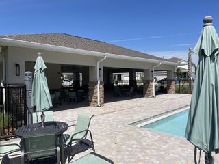 A stylish covered pavilion with ample seating and poolside views, perfect for gatherings in Winding Meadows by Pulte Homes (Apopka, FL).