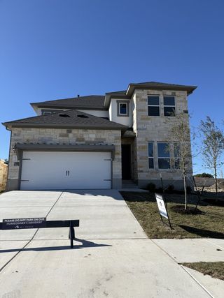Elegant stone facade two-story home in Cedar Brook by M/I Homes, Leander, TX, with a spacious driveway and garage.