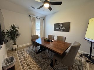 A sophisticated meeting room with a wooden table, upholstered chairs, and elegant decor, featuring a stylish ceiling fan.