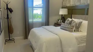 A cozy bedroom with soft lighting, neutral tones, and a plush bed adorned with textured cushions.