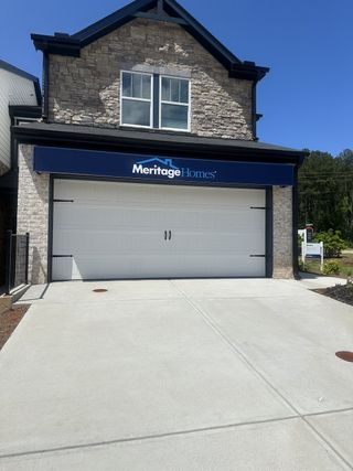A modern stone facade with a spacious garage in Eagles Hill by Meritage Homes (Stockbridge, GA).