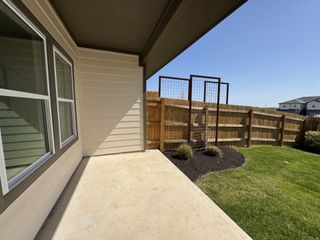 A serene backyard patio with lush grass and wooden fencing, perfect for relaxation in a suburban setting.