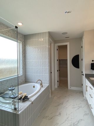 A modern bathroom with a sleek bathtub, elegant tiles, and bright natural light creating a serene space.