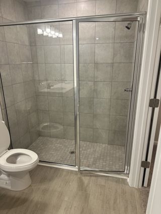 A modern bathroom featuring a sleek glass shower, tiled walls, and wood-look flooring for a clean, contemporary feel.