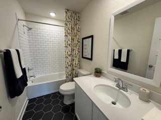 A modern bathroom featuring a subway-tiled bath, hexagonal floor tiles, and sleek white vanity.
