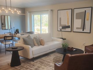 A chic living and dining area with modern décor, abstract artwork, and warm tones in Copes Landing by D.R. Horton (Jacksonville, FL).