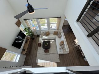 Model Home A spacious, airy living room with a sectional sofa, large windows, and modern decor, viewed from above.