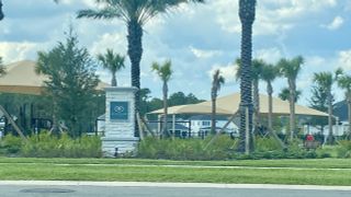 A welcoming entrance with palm trees and a community sign in Reflections at Nocatee by Providence Homes (Nocatee, FL).