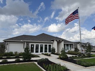 Street view A beautifully designed single-story model home with a manicured lawn and inviting entryway in Riverbend at Double Eagle by Meritage Homes (Cedar Creek, TX).