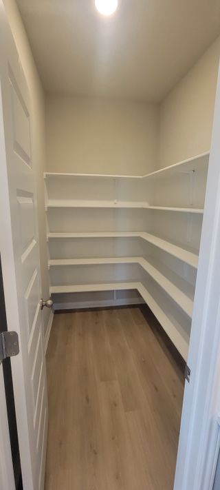 Model Home A spacious pantry with light wood flooring and white wrap-around shelving.