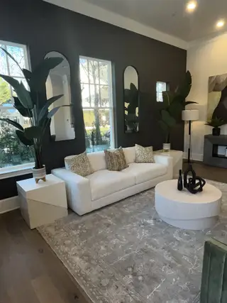 A modern living room with a sleek white sofa, abstract decor, and large mirrors enhancing the space's elegance and light.