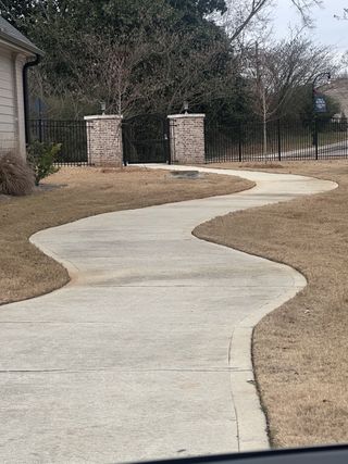 A charming landscaped pathway with brick and wrought iron gate in Cottages at Noble Village by Seed Capital Investments, LLC (Lilburn, GA).
