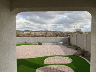 A scenic backyard with a paved patio and lush landscaping, offering mountain views under a cloudy sky.