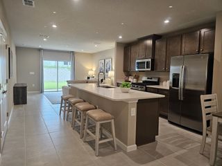 Model Home A modern kitchen with a sleek island, stainless steel appliances, and cozy seating in a bright, open-concept layout.
