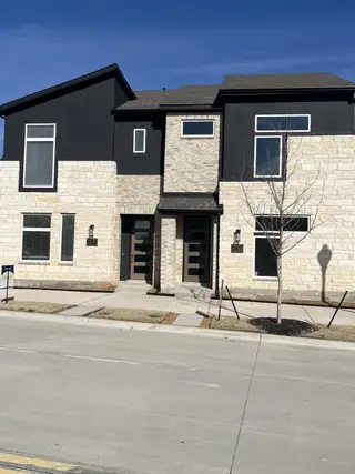 Street view A modern two-tone home with a sleek design and bright flags in Collin Creek by Brightland Homes (Plano, TX)