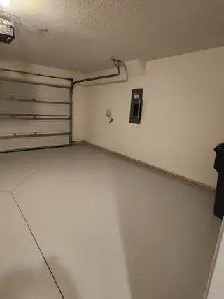 A spacious, clean garage with a smooth concrete floor and overhead door, perfect for parking and storage.