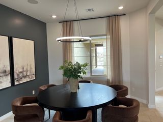 Model Home A modern dining area features a sleek round table, leather chairs, abstract art, and a chic pendant light, creating a stylish ambiance.