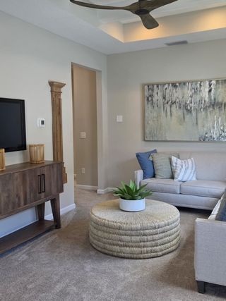 A cozy living room with a neutral sofa, textured ottoman, abstract art, and a modern TV console.