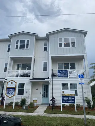 A modern white townhouse with clean lines and a welcoming entry in North Beach Townhomes by Dream Finders Homes (Jacksonville, FL).