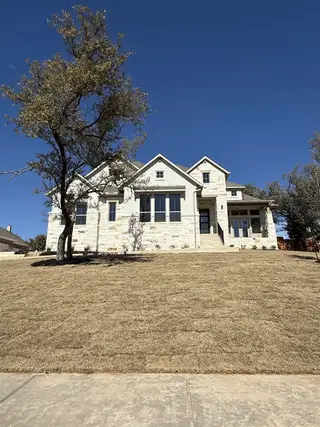 Street view A beautiful modern farmhouse with striking dark trim and an elevated front yard in Lakeside at Tessera by Coventry Homes (Lago Vista, TX).