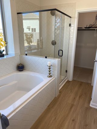 Model Home A modern bathroom with a glass shower, herringbone tile walls, and wood-look flooring for a stylish, elegant feel.