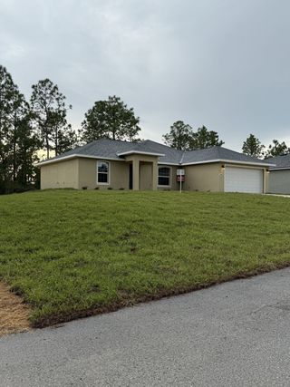 A modern single-story home with a spacious lawn in Marion Oaks by Perfect Deed Homes (Ocala, FL).