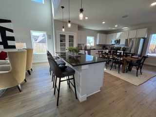 A modern kitchen with a large island, sleek black countertops, and open dining area. Bright and spacious with elegant fixtures.
