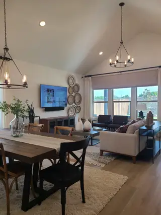 Model Home An inviting living area with vaulted ceilings, elegant chandeliers, and cozy seating, perfect for entertaining and relaxation.