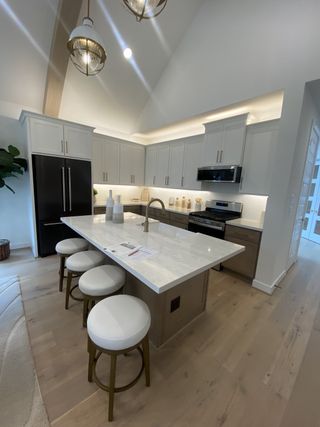 A modern kitchen with vaulted ceilings, marble island, stylish lighting, and sleek cabinetry.