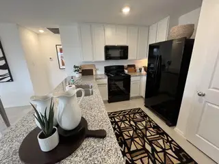Model Home A modern kitchen with white cabinets, granite countertops, and black appliances for a sleek contrast.