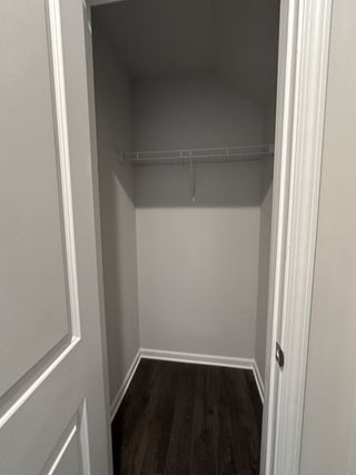 A spacious walk-in closet with sleek dark flooring and neutral walls, perfect for ample storage and organization.