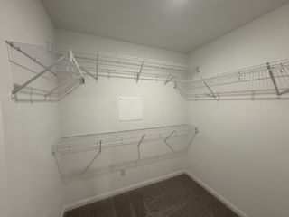 Model Home A spacious walk-in closet with white wire shelving and plush carpeting, perfect for organized storage.