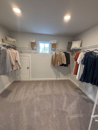 A spacious walk-in closet with soft carpet, ample shelving, and modern lighting. Perfect for organized storage.