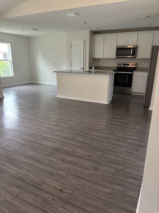 An open kitchen with sleek cabinetry, granite countertops, and wood-like flooring, featuring stainless steel appliances.